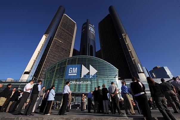 General Motors employees and visitors watch a large video monitor outside the GM World Headquarters.